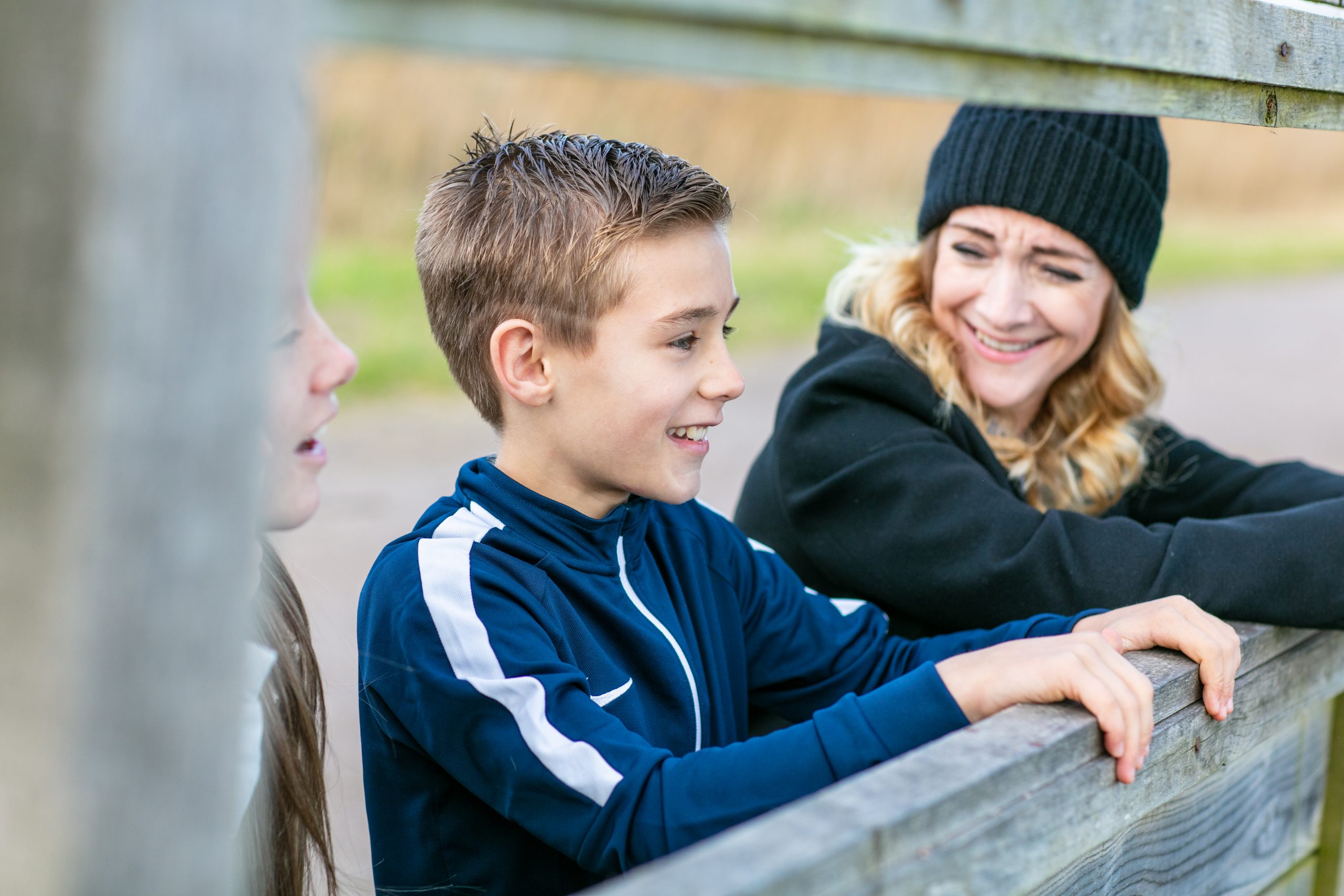 Boy smiling with Woman on leaning on fence