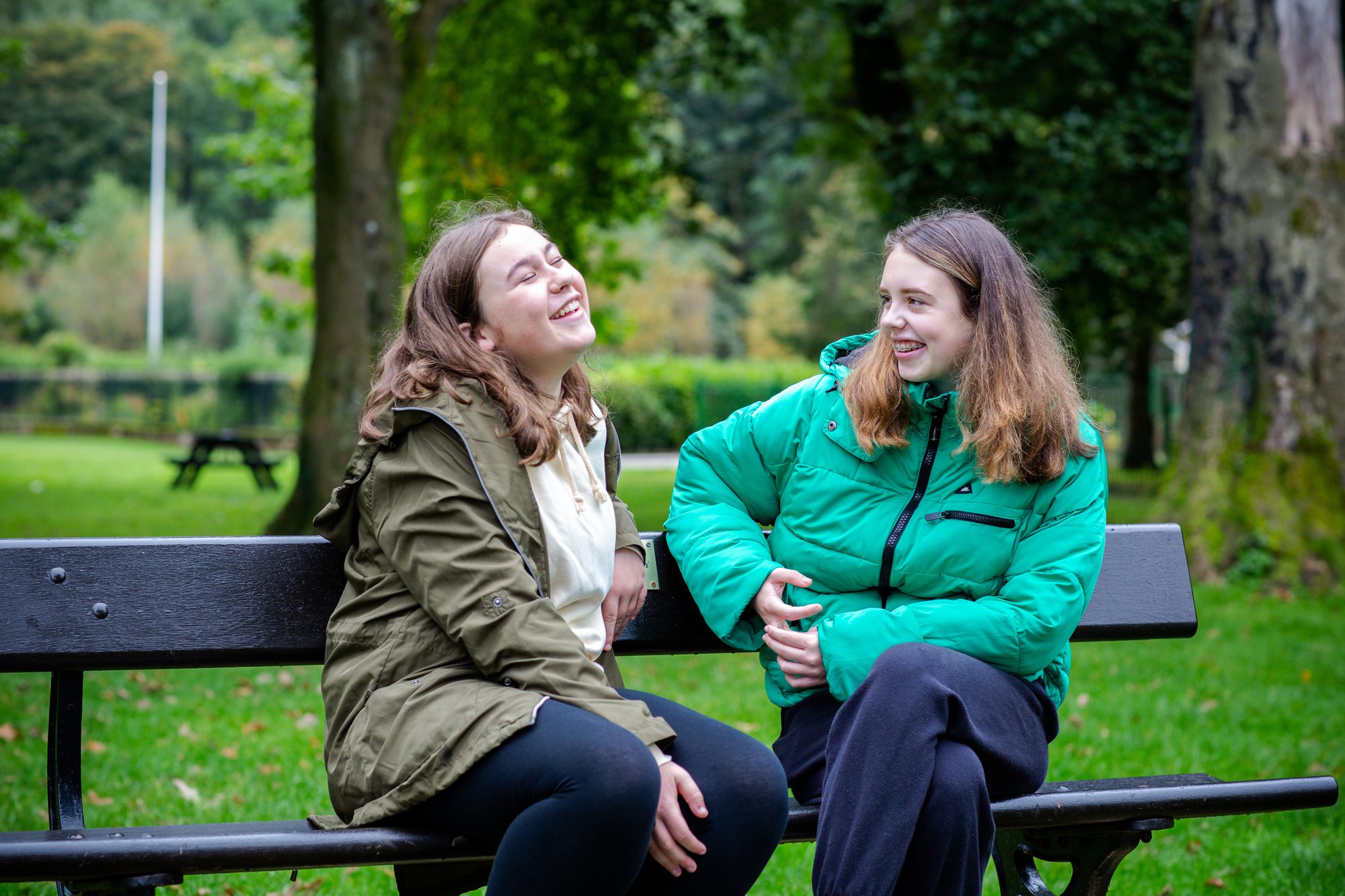 two girls laughing on a park bench