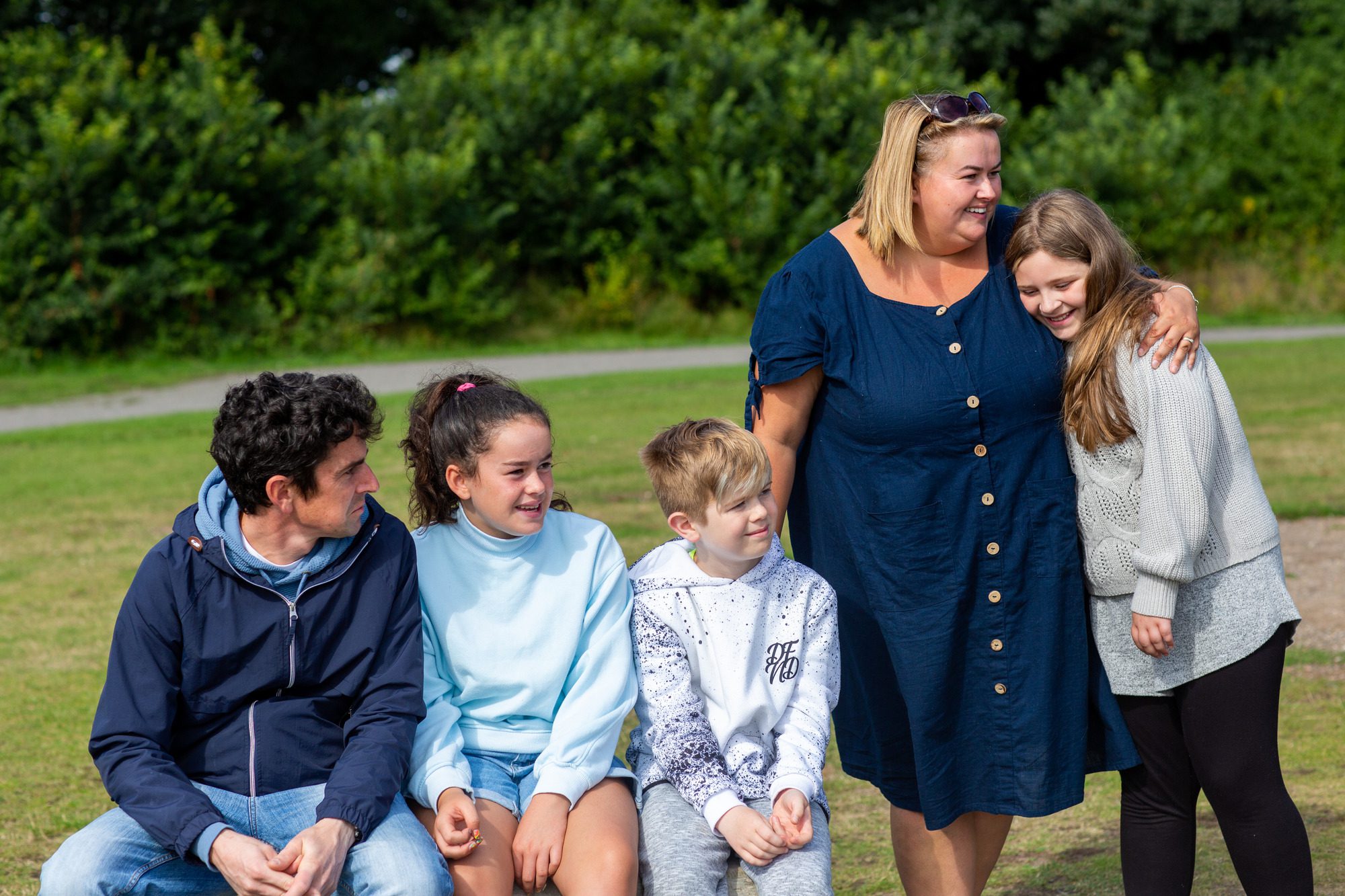 family of five smiling and hugging outdoors