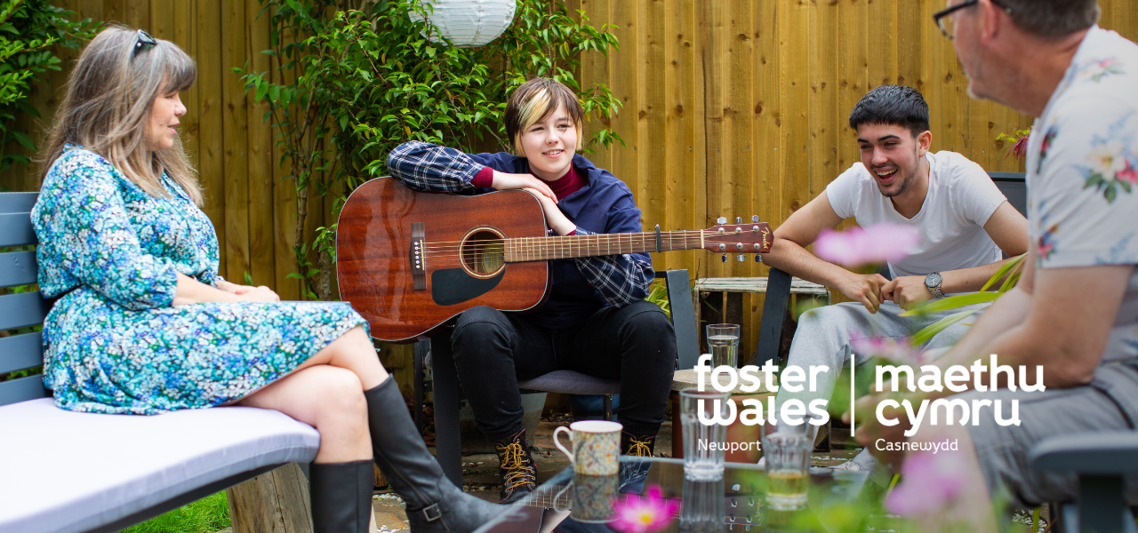 foster wales two adults with 2 young men, one with a guitar
